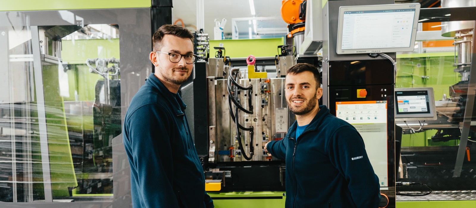 Picture of Hamid Isič and Mevljudin Memedi in front of an injection moulding machine.